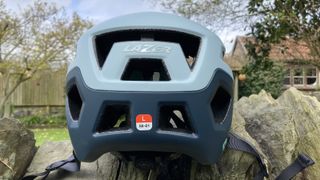 Rear view of Lazer Coyote KinetiCore mountain bike helmet on a stone wall