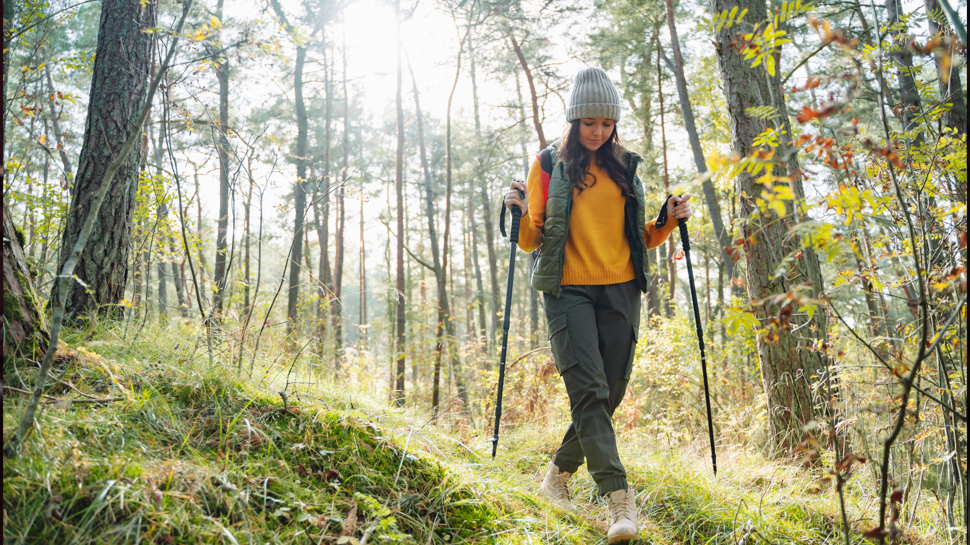A woman hiking with trekking poles through the wood