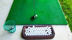 A driver head behind a ball at the driving range