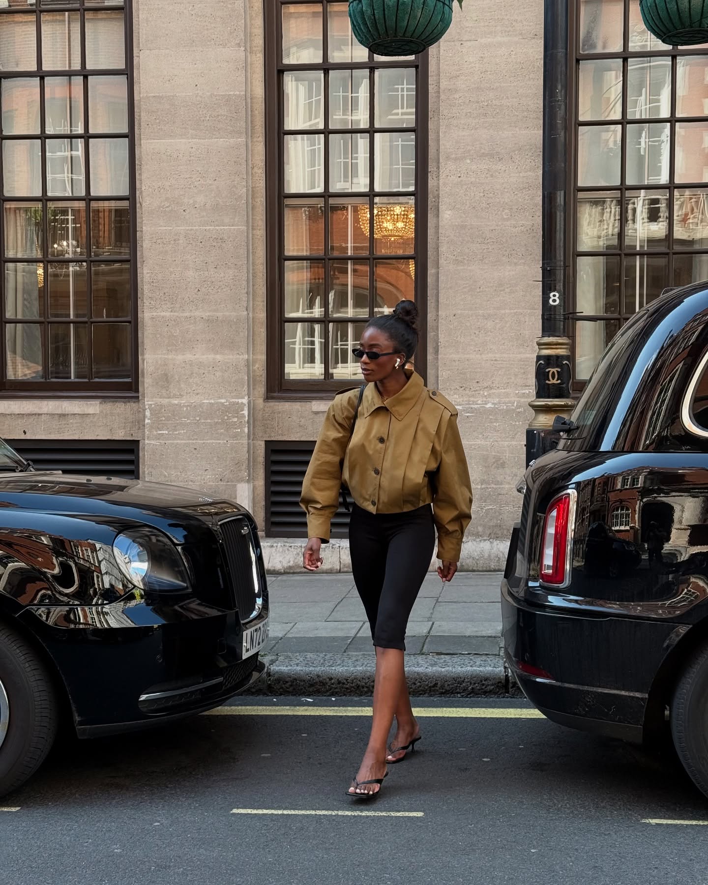 An image of Liv Madeline wearing a khaki cropped jacket with capri leggings and flip-flops.