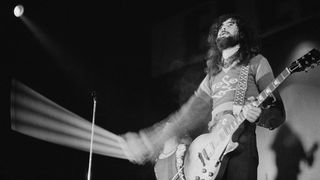 Jimmy Page onstage in 1971, bow in hand, wearing a warm sweat and rocking a Les Paul Standard