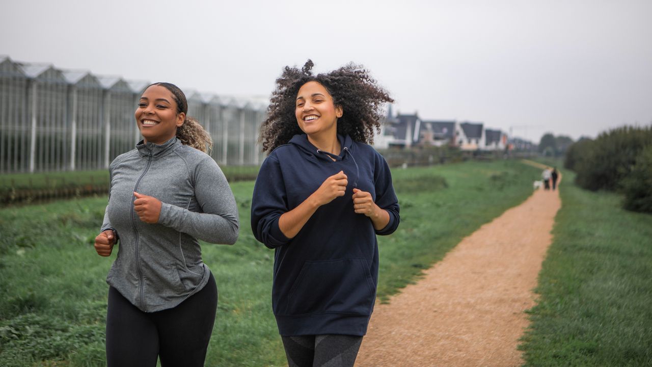 Two women running along gravel path