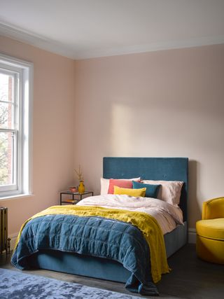 pink bedroom with teal bed and accents of yellow