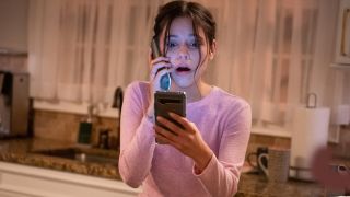 Jenna Ortega checking her phone in horror in Scream.