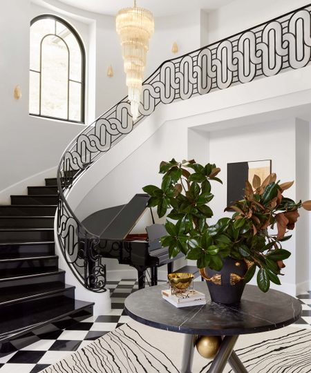 entryway with large black and white staircase, round coffee table and large central light