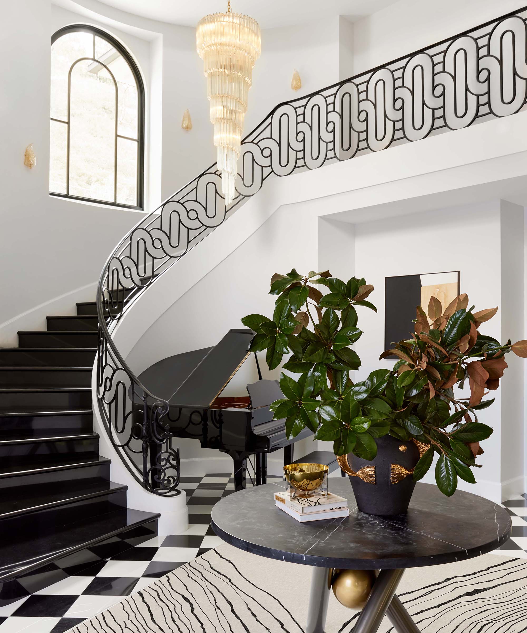 entryway with large black and white staircase, round coffee table and large central light