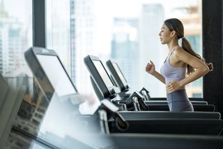 Exercise motivation: Side view of Young Asian women athlete running or jogging on treadmill in a hotel sport club.