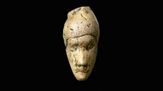 Ivory portrait head of a Stone Age woman against a black background