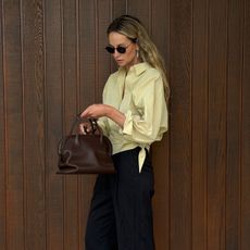 Anouk wearing a butter yellow shirt and brown The Row bag