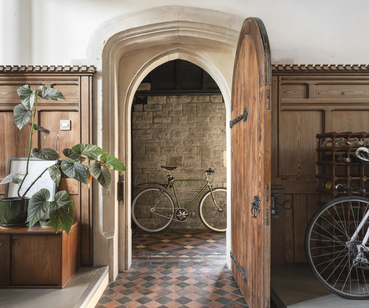 Arched wooden door open with a bike behind it