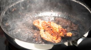 meat being cooked in a smoky frying pan