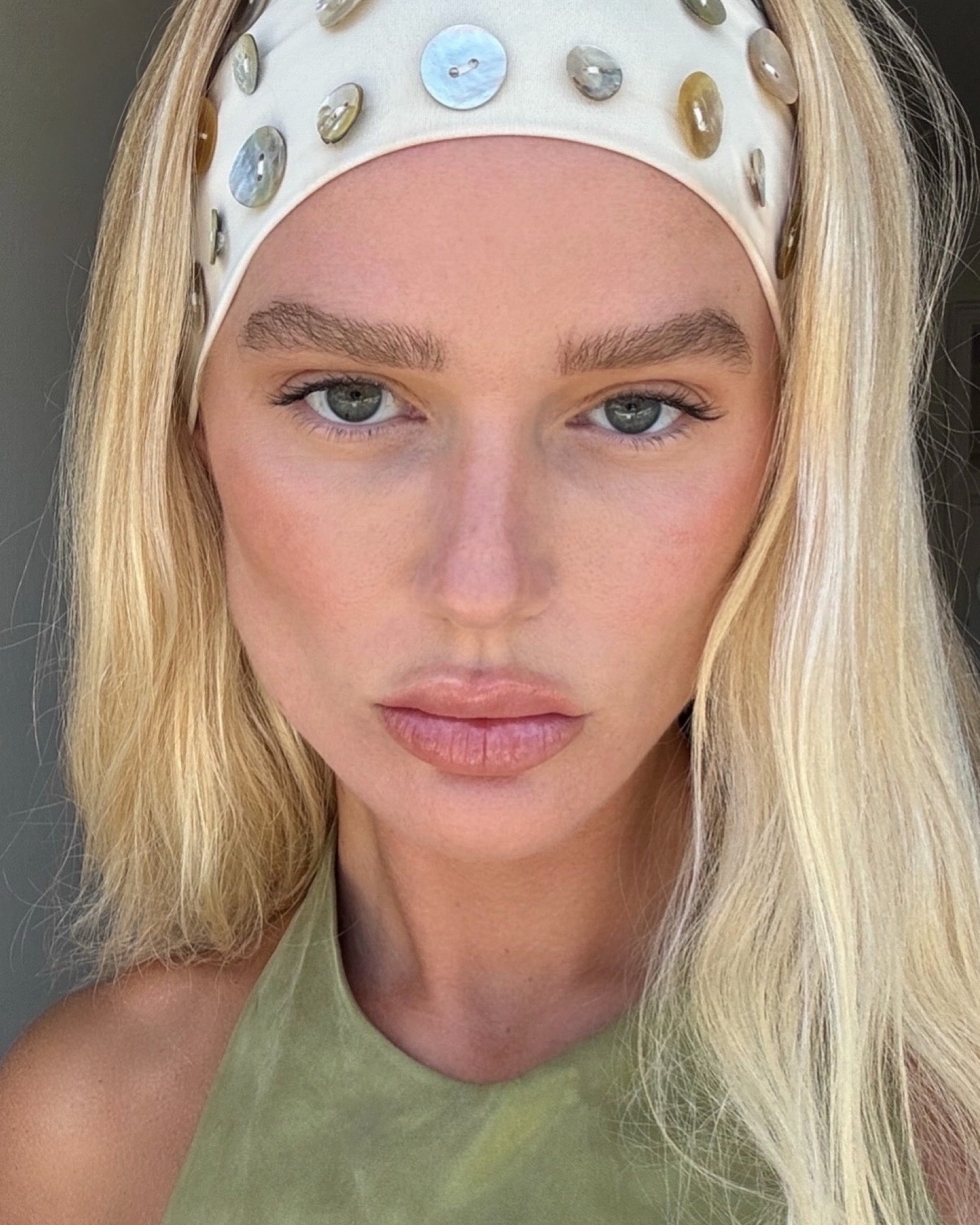 A woman taking a selfie wearing a thick white headband with creamy, bright blonde hair