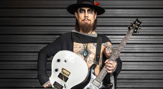 Jane's Addiction's Dave Navarro is open-shirted, wearing a flower in his hat as he is photographed with his signature PRS electric guitars