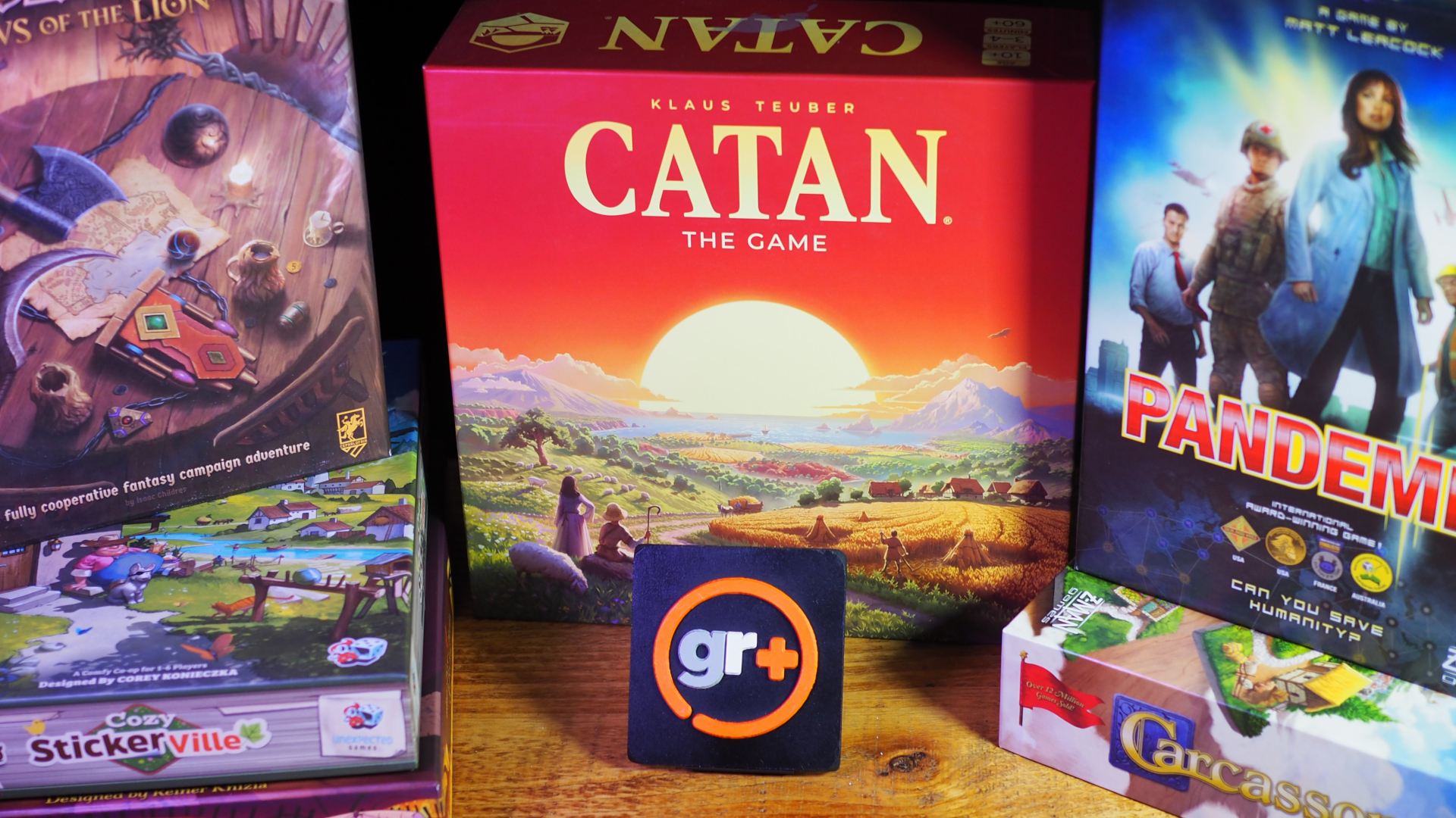 A selection of board games laid out on a wooden table, behind a GamesRadar+ logo