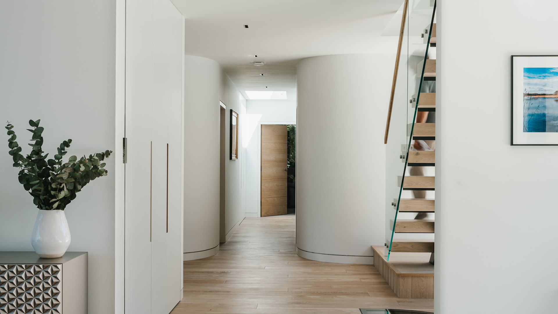 modern hallway with open tread staircase and curved wall