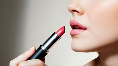 Woman applying lipstick - stock photo