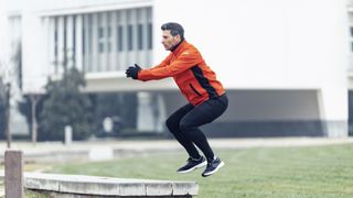 Male runner doing jumping squats at a public park
