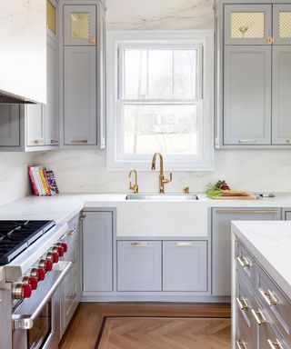 modern kitchen with gray cabinets and white butler sink with brass tap
