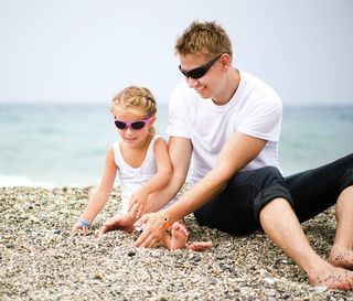 Dad plays with daughter on beach.