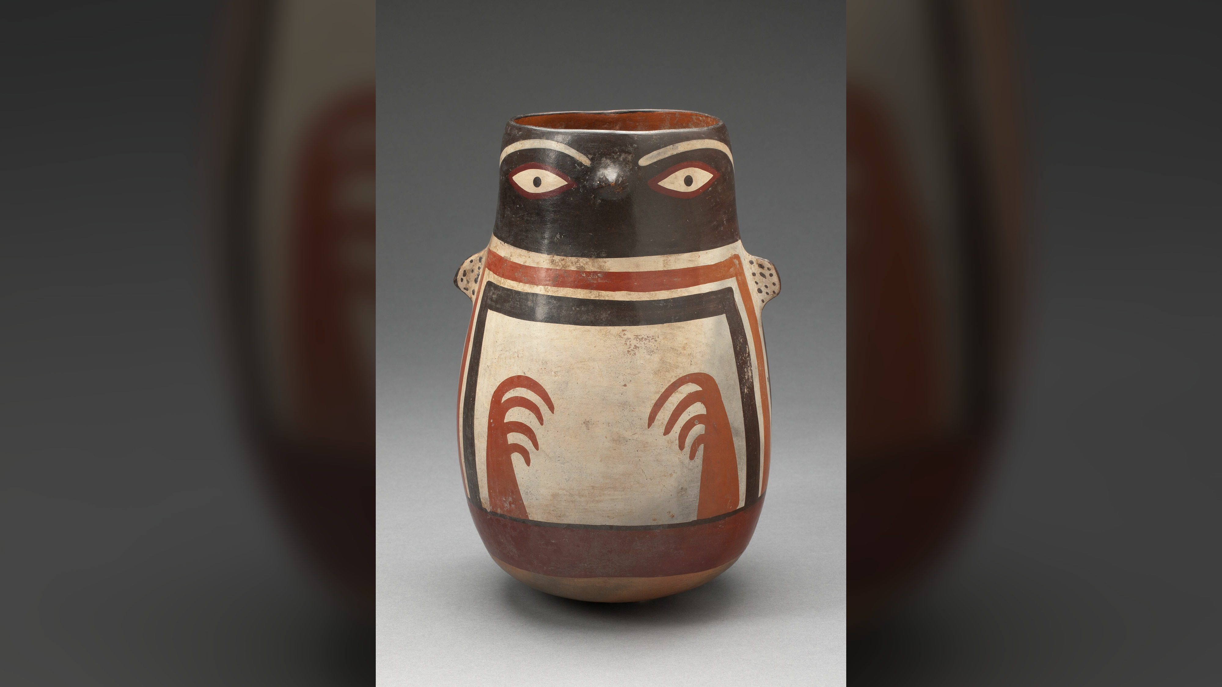 A conical pot that is brown, orange, and cream colored has a tiny beak and arms, representing a Humboldt penguin