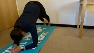 Fitness writer Daniella Gray practicing dolphin plank wall Pilates move at home