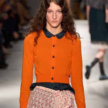 Woman in an orange cardigan and skirt