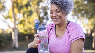 Here's a list of the best water bottles. In this image, a healthy woman holds a reusable water bottle after a workout.