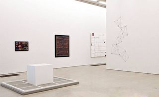 Exhibition space featuring three wall art pieces and a wall drawing of connected lines.