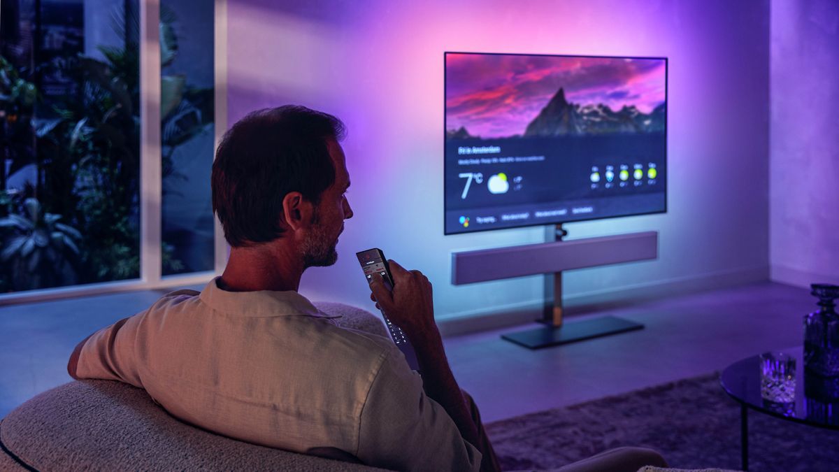 Philips OLED+986 in living room with man using voice remote