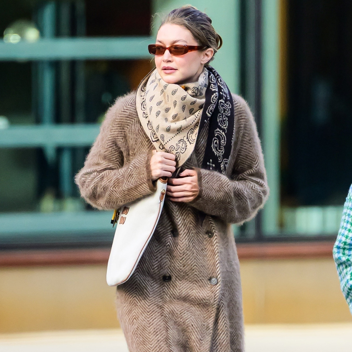Gigi hadid wears a silk scarf, miu miu bag, and a double breasted wool coat.