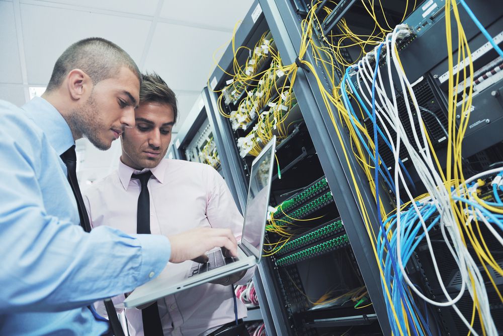 Two engineers looking at servers with lots of messy cables