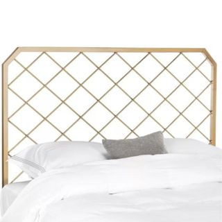A brushed gold criss-cross headboard with white sheets and a gray throw pillow