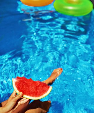 pool party ideas woman by pool holding slice of watermelon