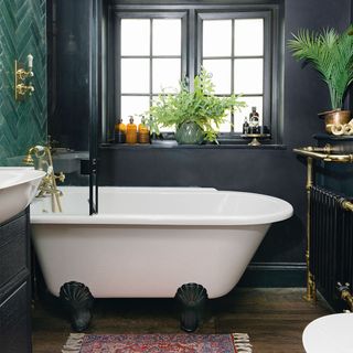 black bathroom with green tiles and freestanding bath