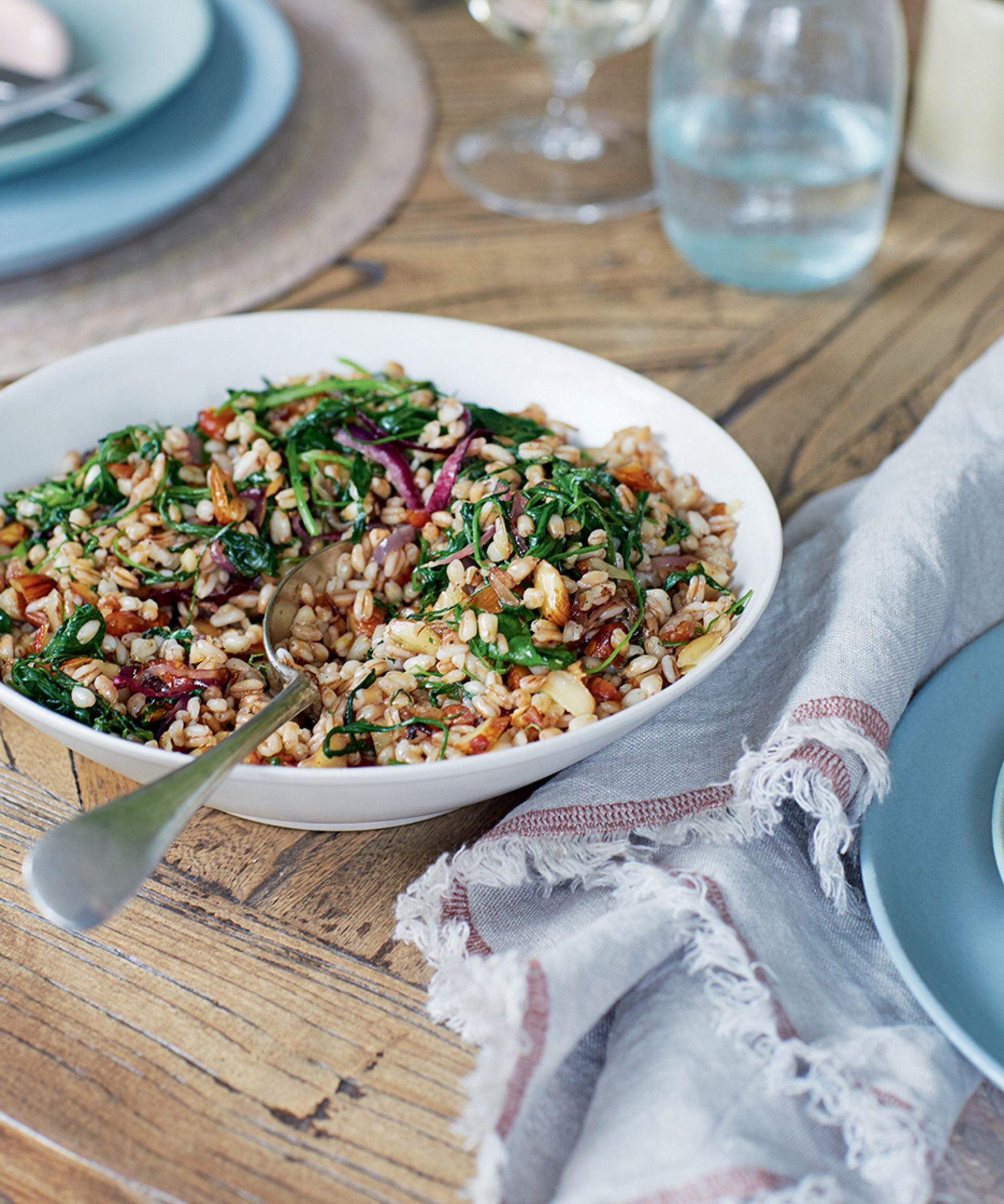 Spelt, almond and Arugula salad in a white bowl