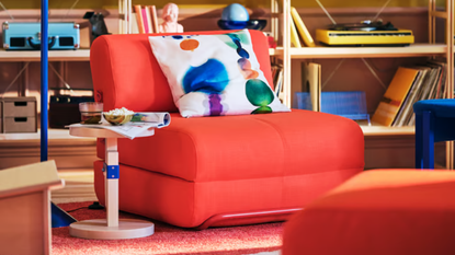 a bright red chair bed from ikea with a decorative pillow on top
