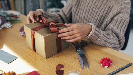 Hands of an Anonymous Woman Packing Christmas Presents for her Loved Ones - stock photo