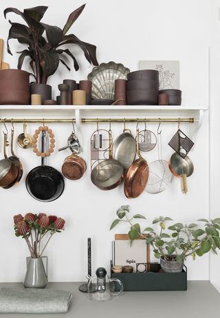 Brass kitchen hanging rails for pots and pans, an example of stylish kitchen planning by nest