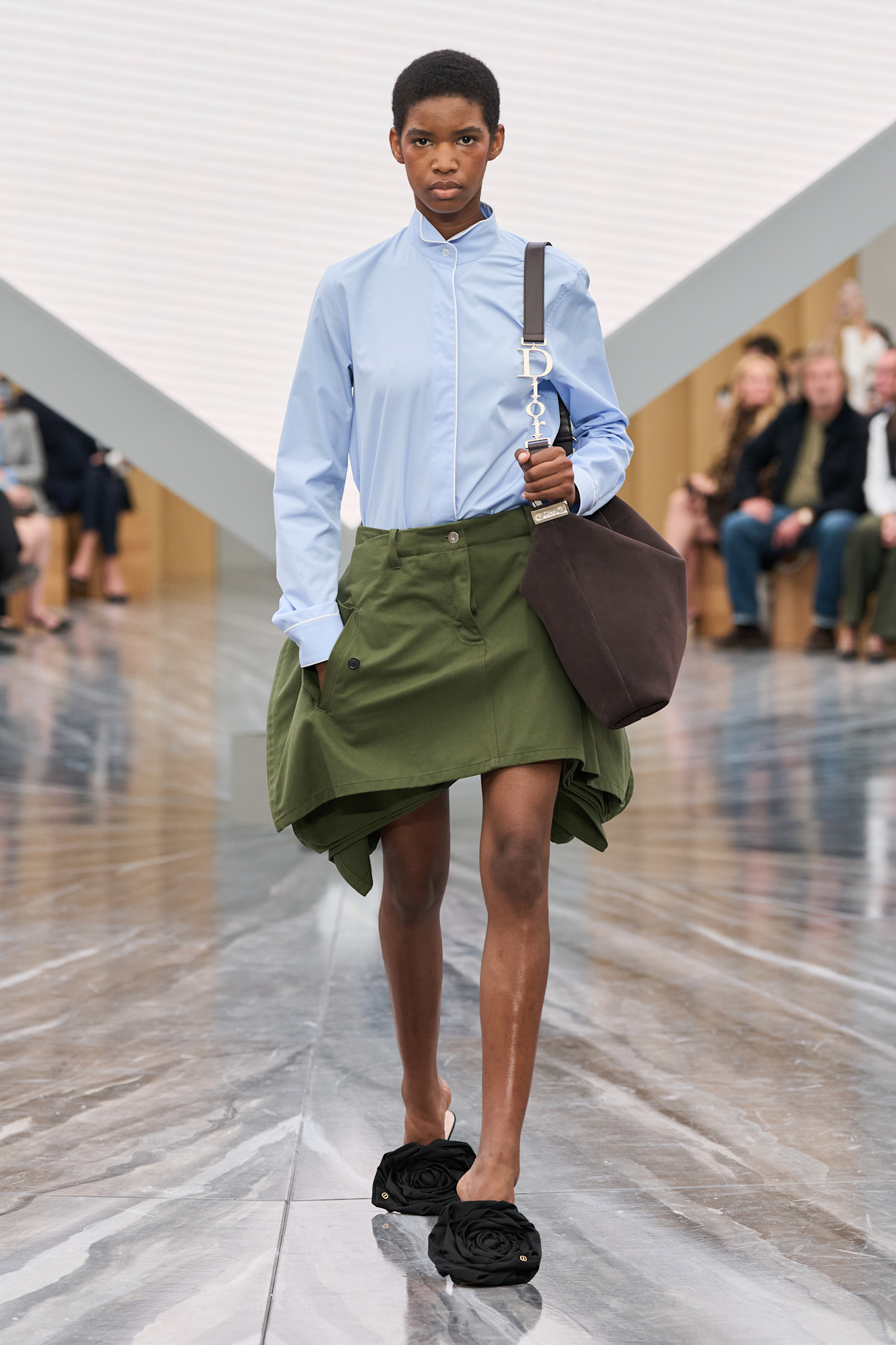 a model carries the dior diorly bag on the runway.