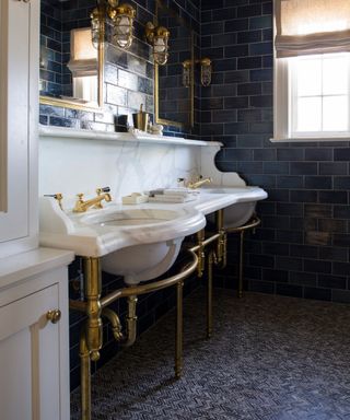 blue tiled bathroom with herringbone floor and large antique vanity unit with brass accessories