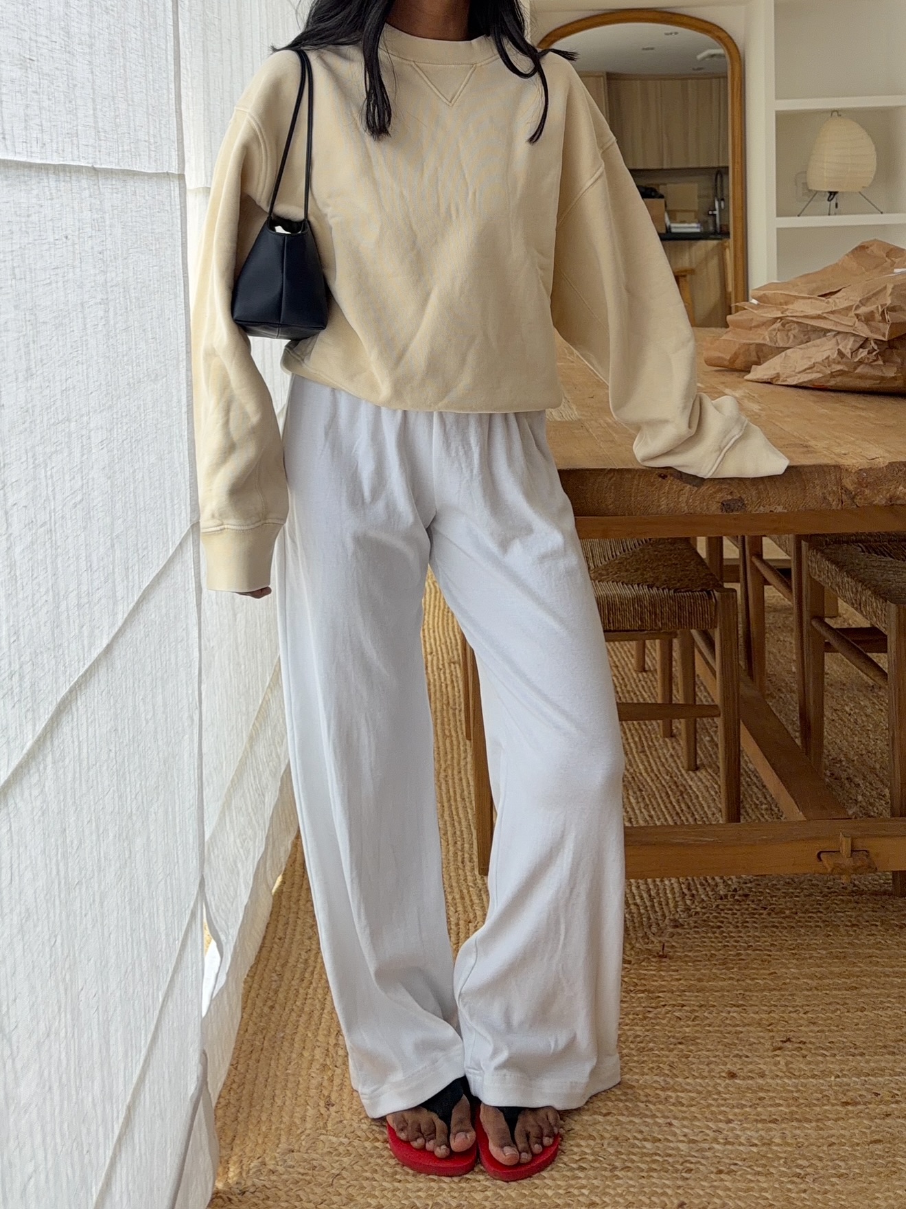 monikh dale wears a cream jumper, white linen trousers and red flip flops from The Row