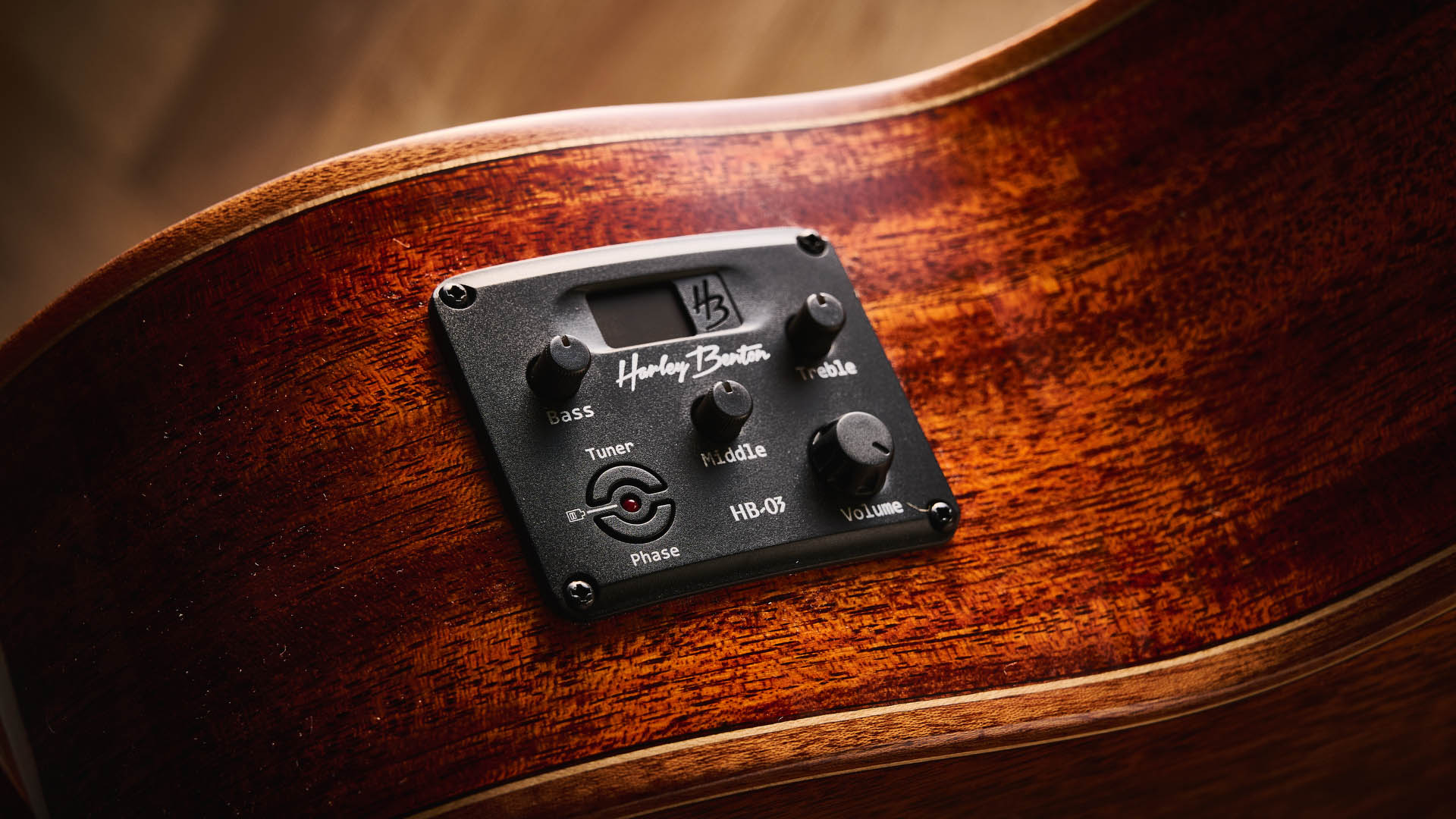 Harley Benton CLC-650SM-CE: the affordable cutaway electro-acoustic has a black top, natural back and sides, with an attractive arm-rest and tortoiseshell pickguard, and is here photographed against a wooden floor.