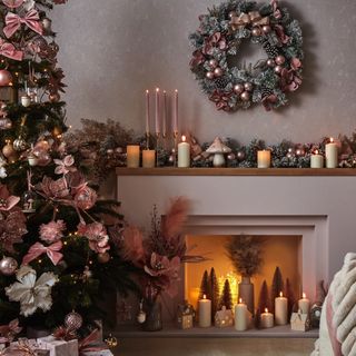 a modern fireplace filled with candles and christmas tree and wreath