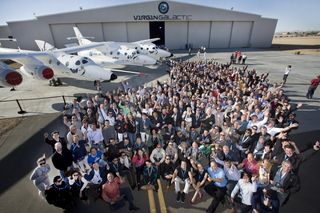 A number of Virgin Galactic's future astronauts gathered with Sir Richard Branson (center) for a group photo last year at Virgin Galactic's Final Assembly, Integration and Test Hangar (FAITH) in Mojave, Calif. Nearby is the WhiteKnightTwo mated with SpaceShipTwo.