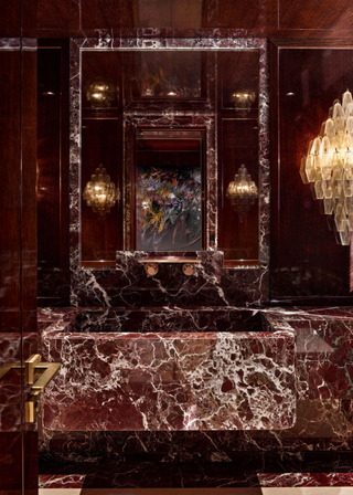 A super lux powder room covered in rosso levanto marble