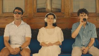 L-R: Patrick Schwarzenegger, Sarah Catherine Hook and Sam Nivola sitting on a bench in HBO's "The White Lotus" season 3