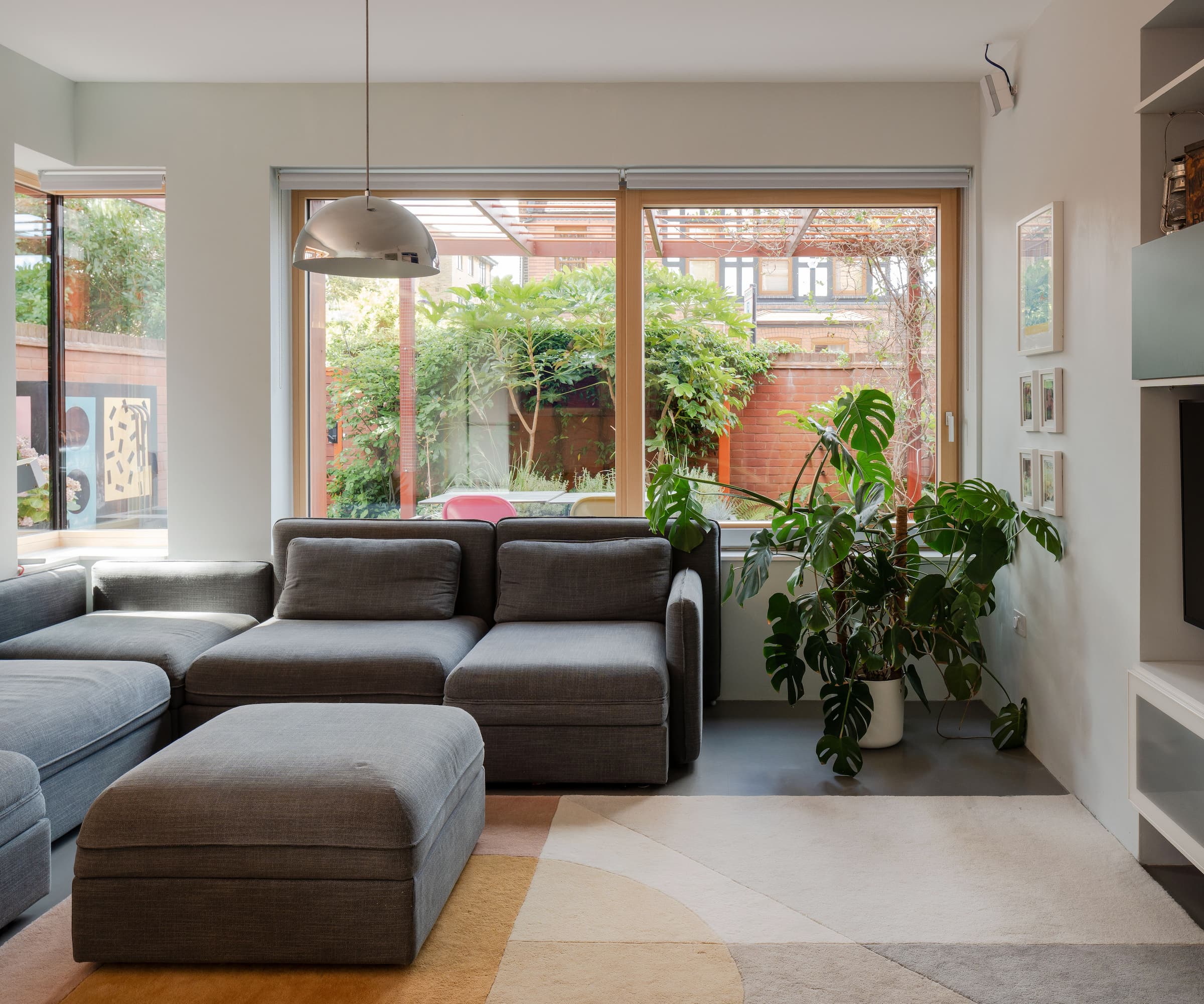 A living room with grey sofas and floor to ceiling windows