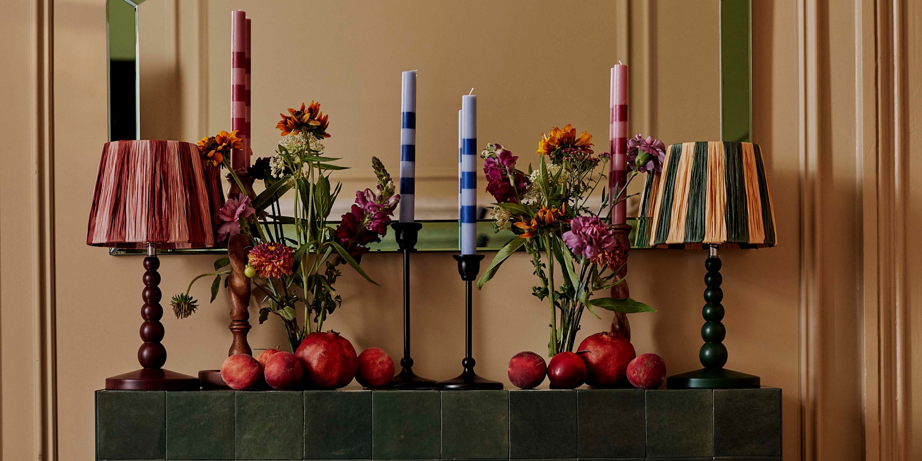 A green mantlepiece with two bobbin lamps and four candles on top