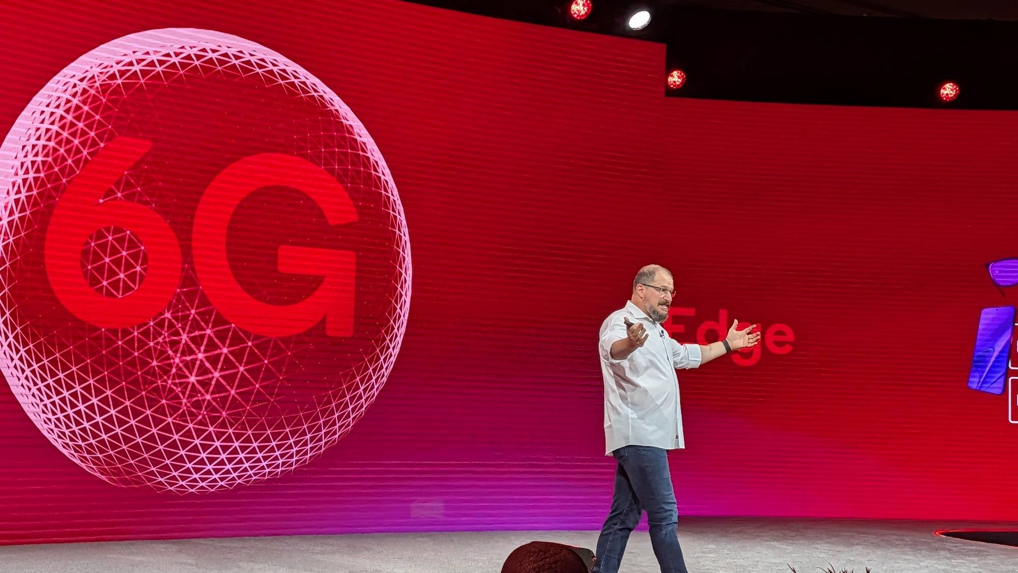 Qualcomm CEO Cristiano Amon on stage with 6G graphic concept behind him