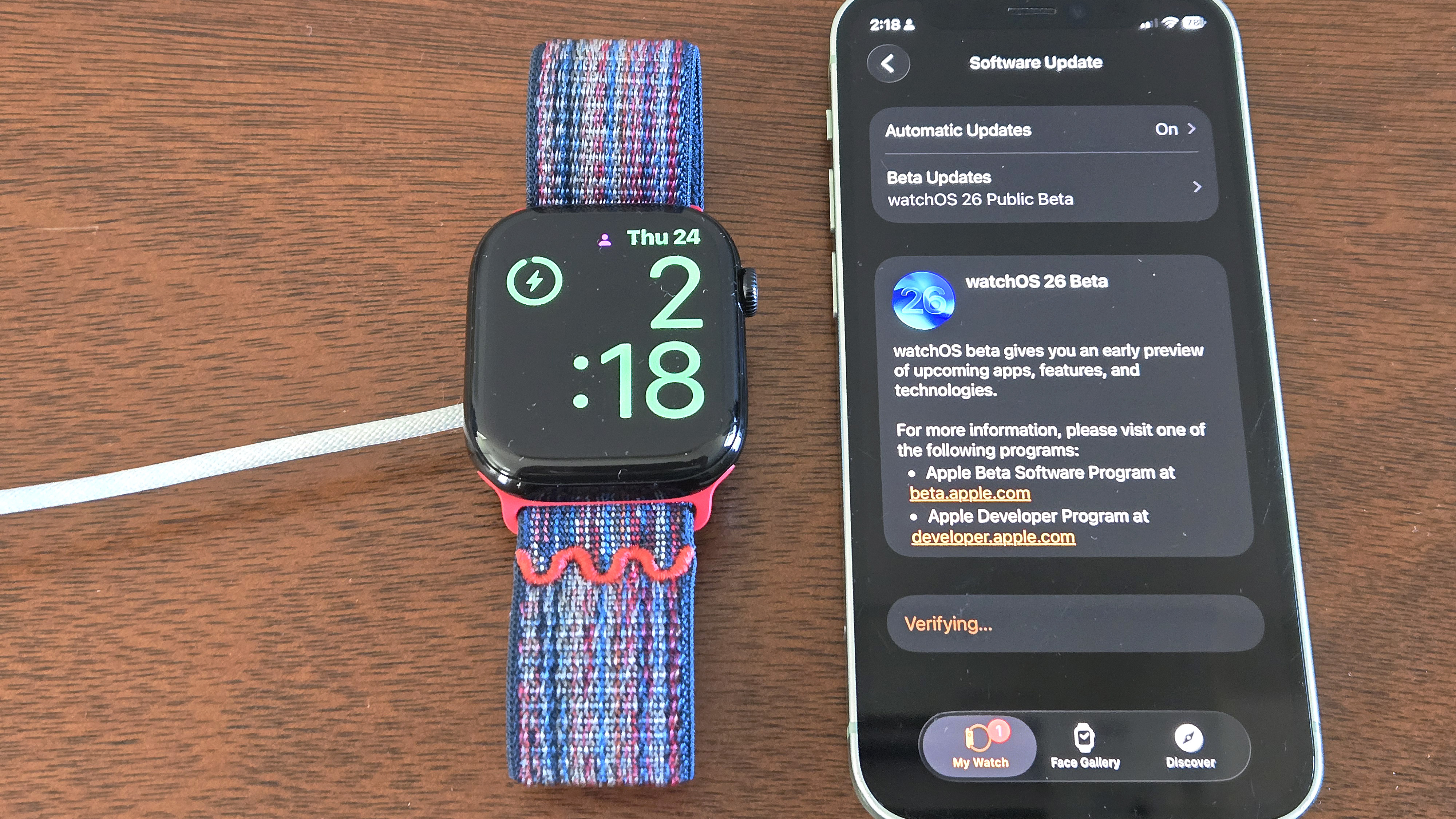Close-up of the installation process for watchOS 26 showing an Apple Watch Series 10 and iPhone 12 Mini